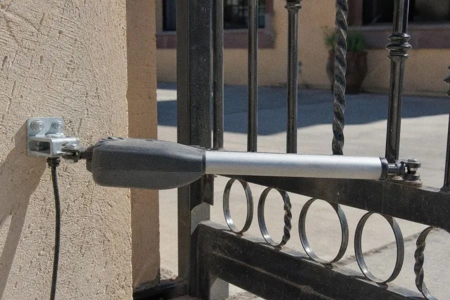 Pistón automático montado en un portón de herrería de dos hojas