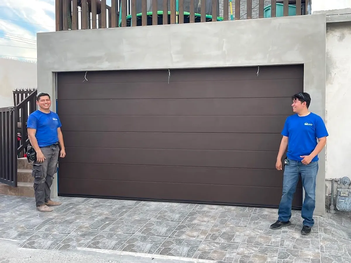 Dos técnicos de AutoGate Electric junto a un portón americano que acaban de instalar
